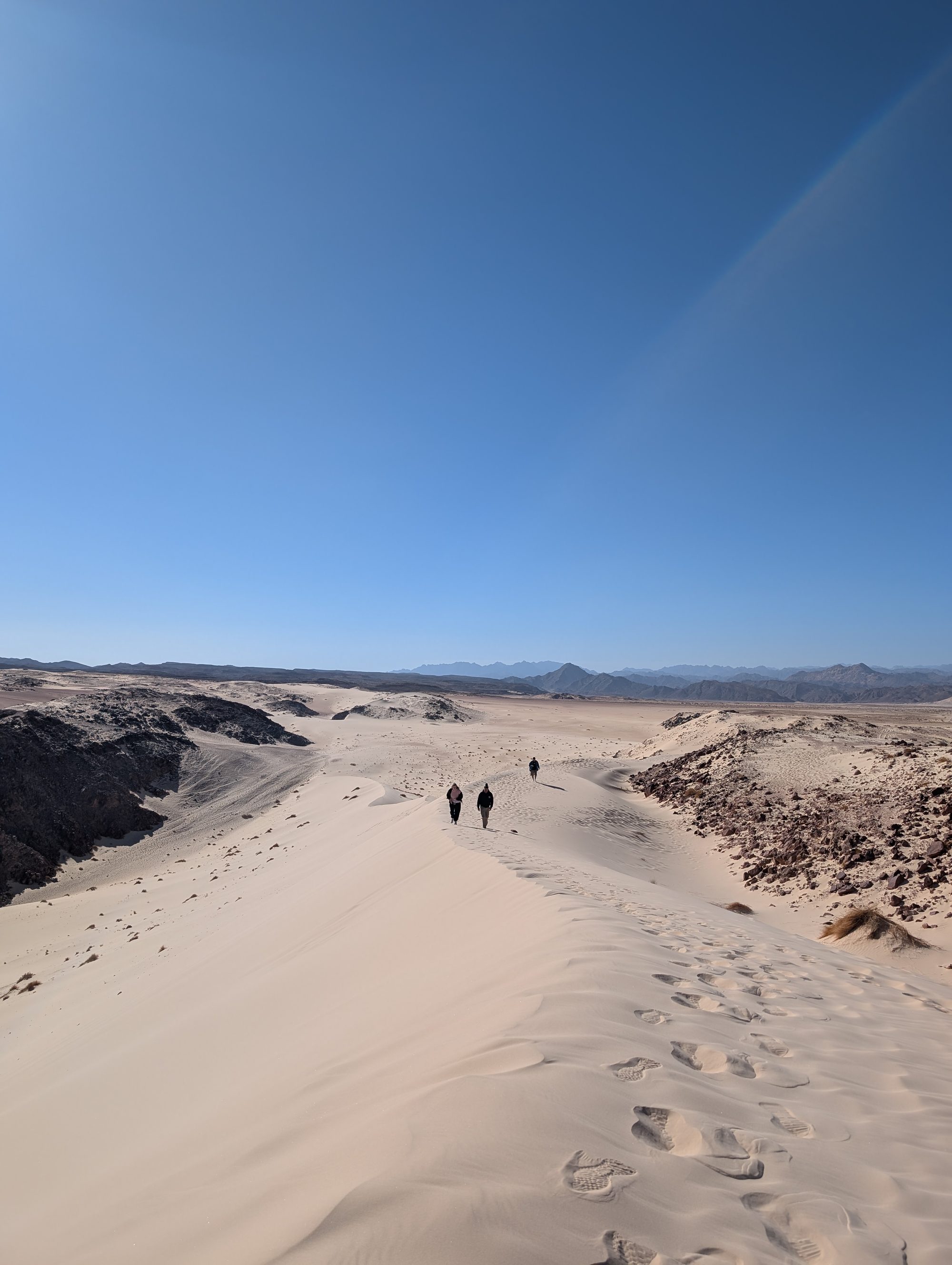 Three people walking the dune ridge